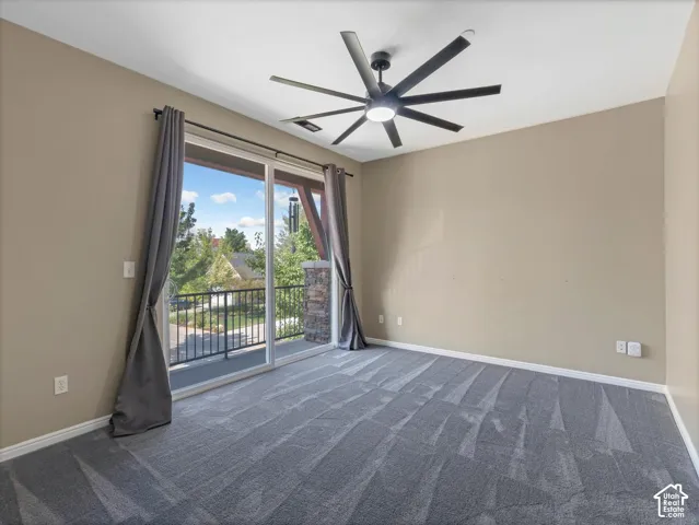 Sliding glass door to balcony, gray patterned carpeting, modern ceiling fan with integrated lighting, neutral wall finishes, white trim