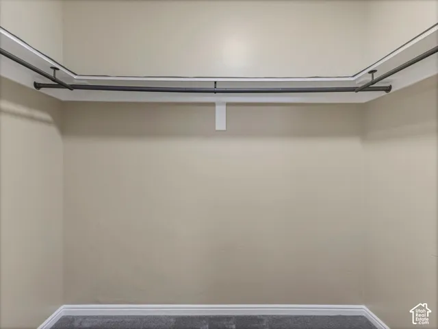 Wraparound clothing rod system, neutral wall paint, and gray carpeted flooring