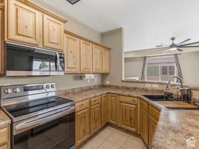 U-shaped kitchen with wood cabinetry, stainless steel appliances, speckled countertops, and a black undermount sink