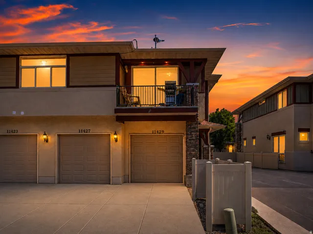 Stucco exterior with stone accents, multiple garage bays, private balcony, and exterior sconce lighting