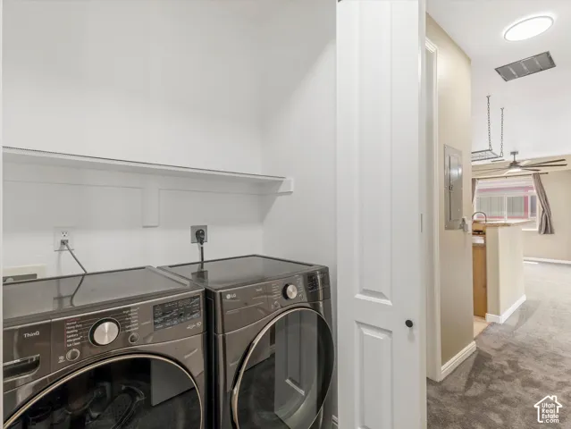 Dedicated laundry area with a white shelving unit, featuring an electrical panel and a white paneled door
