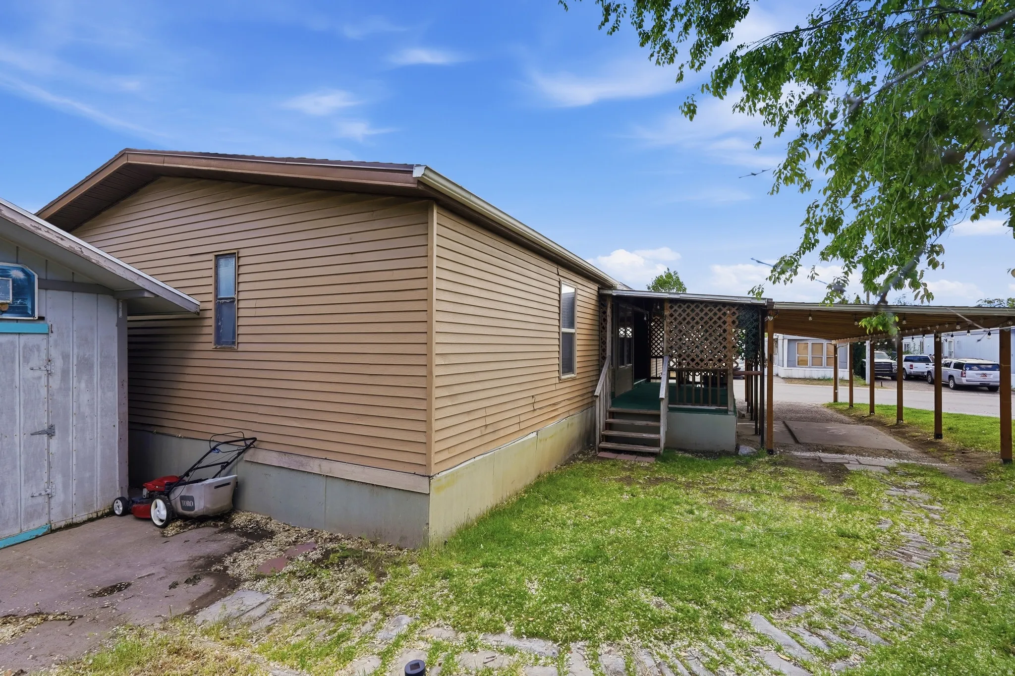 Property exterior featuring tan siding, an enclosed porch with lattice work, and a covered carport