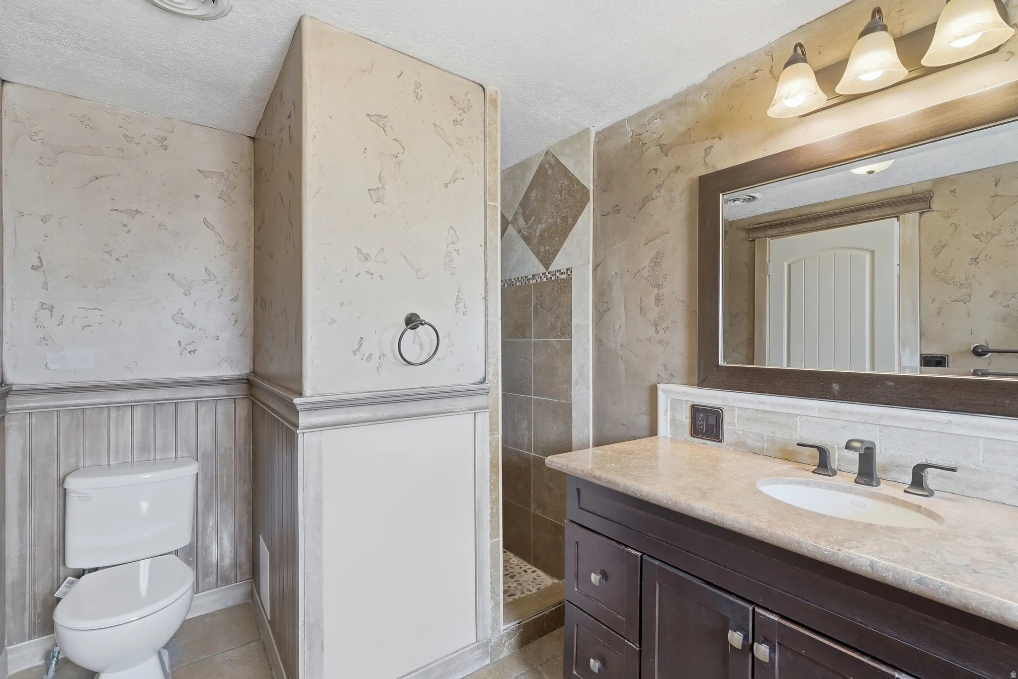 Bathroom featuring a dark wood-finish vanity with a light countertop, under-mount sink, and dark bronze-finish fixtures
