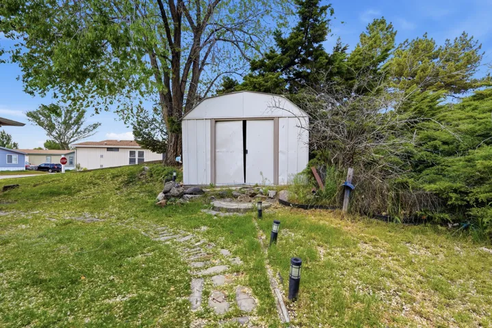 Outdoor storage shed featuring double entry doors and a sloped, shingle-style roof