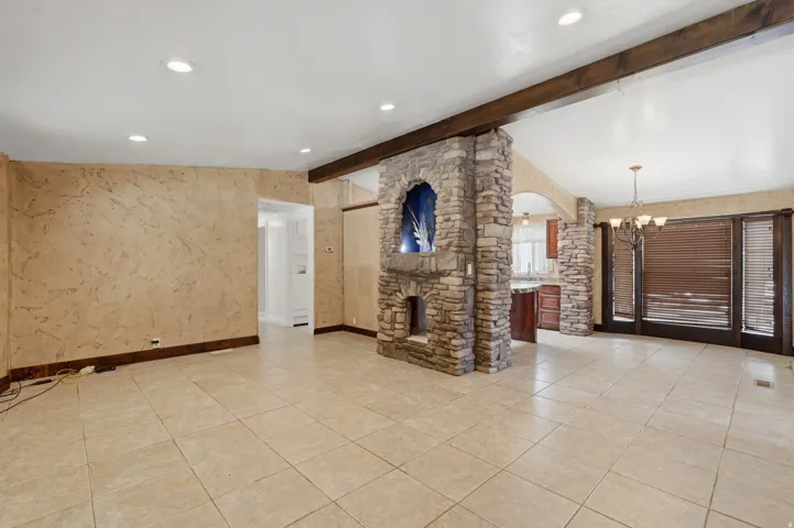Spacious interior featuring large format floor tiling, a stone-clad architectural feature with an arched niche, and a beamed ceiling