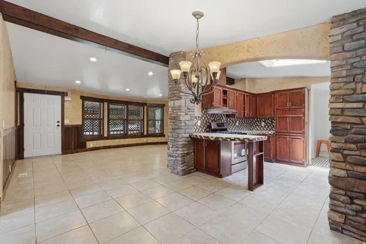 Open-concept living space featuring a kitchen with wood cabinetry, stainless steel appliances, and a tiled backsplash
