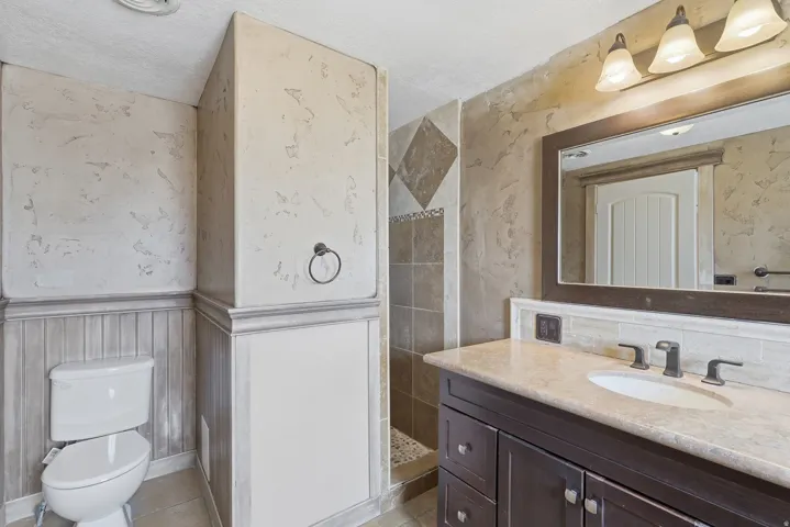 Bathroom featuring a dark wood-finish vanity with a light countertop, under-mount sink, and dark bronze-finish fixtures
