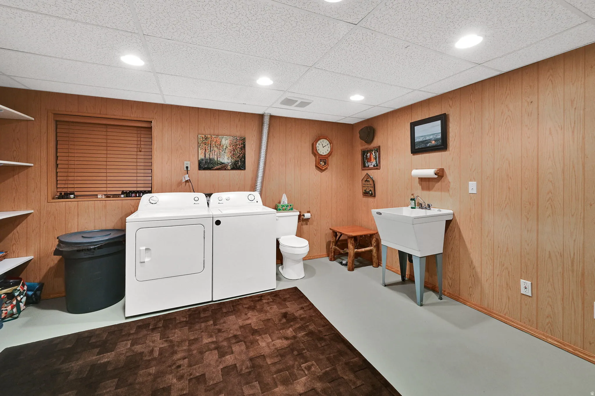 Utility room featuring wood-panel walls and a drop-ceiling with recessed lighting