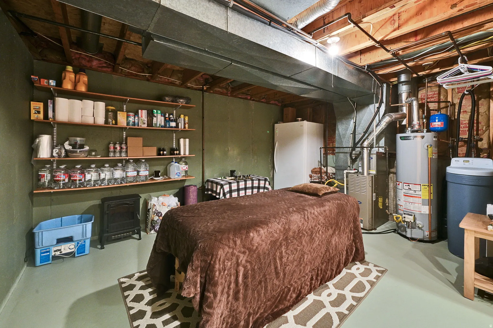 Basement space featuring exposed ceiling joists and ductwork, a water heater, furnace, and water softener system