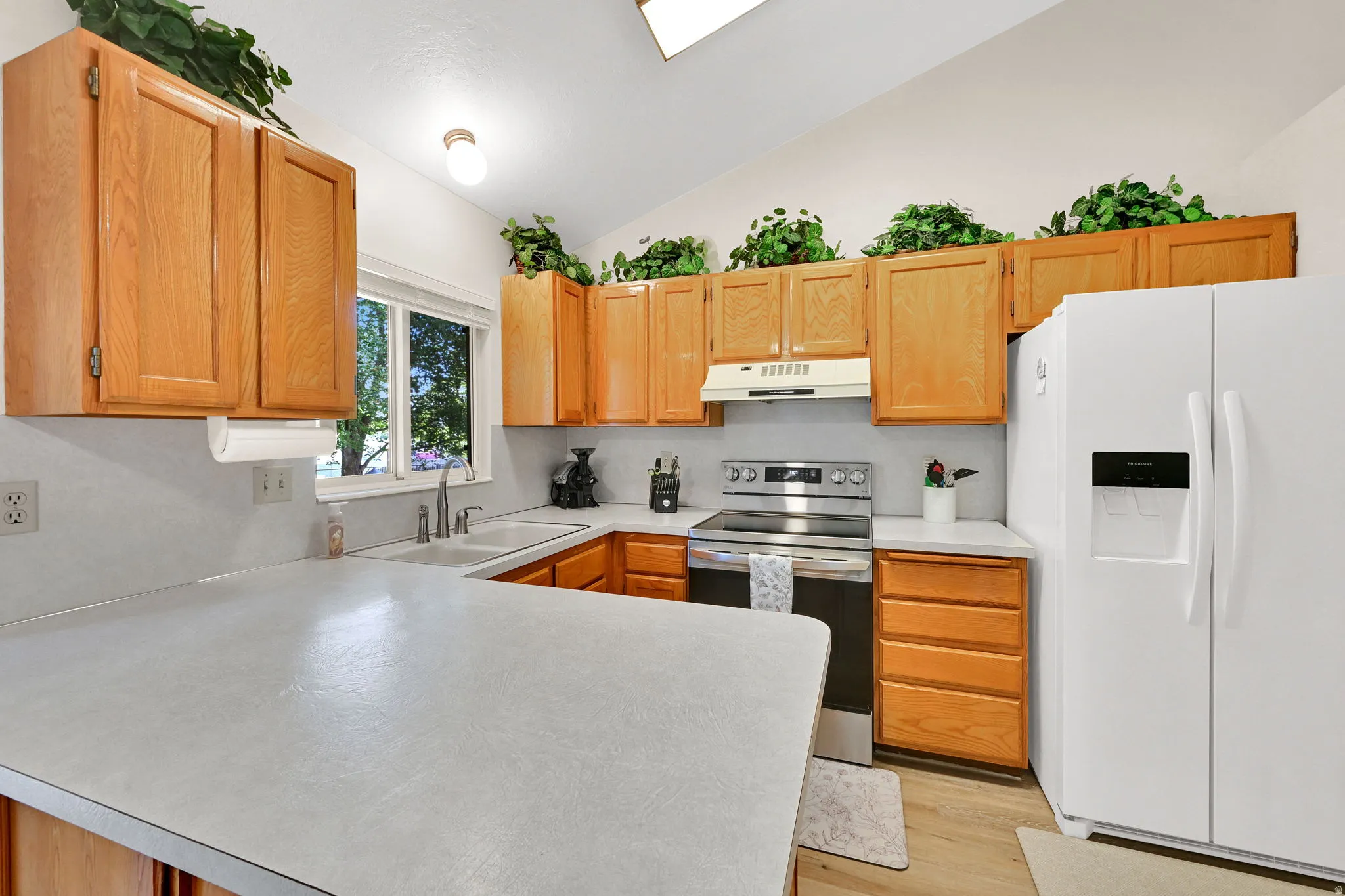 Kitchen featuring light wood cabinetry, white countertops, and a white tile backsplash