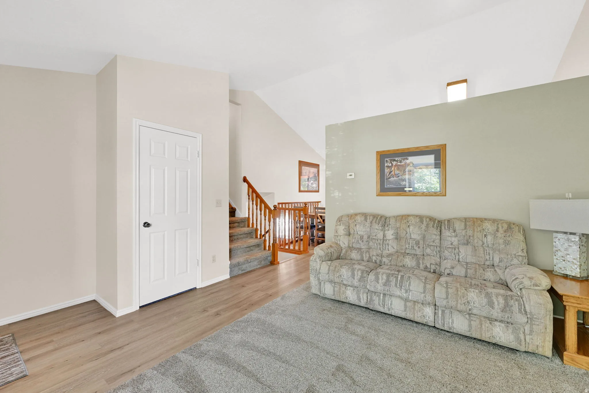 Comfortable family room showcasing neutral décor, wood-finish flooring, and sage green accent wall