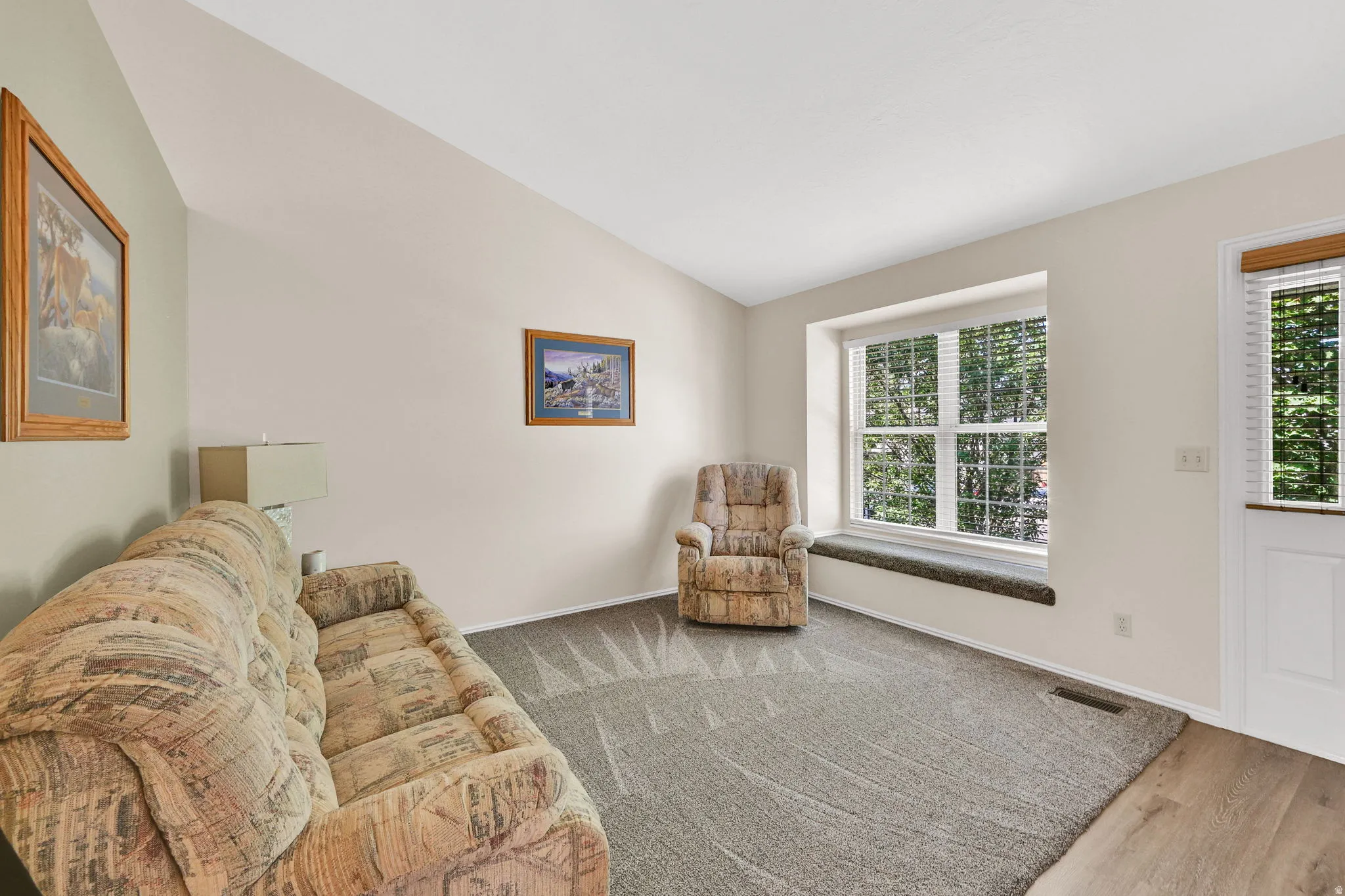 Living space featuring a vaulted ceiling and a large window with a deep sill