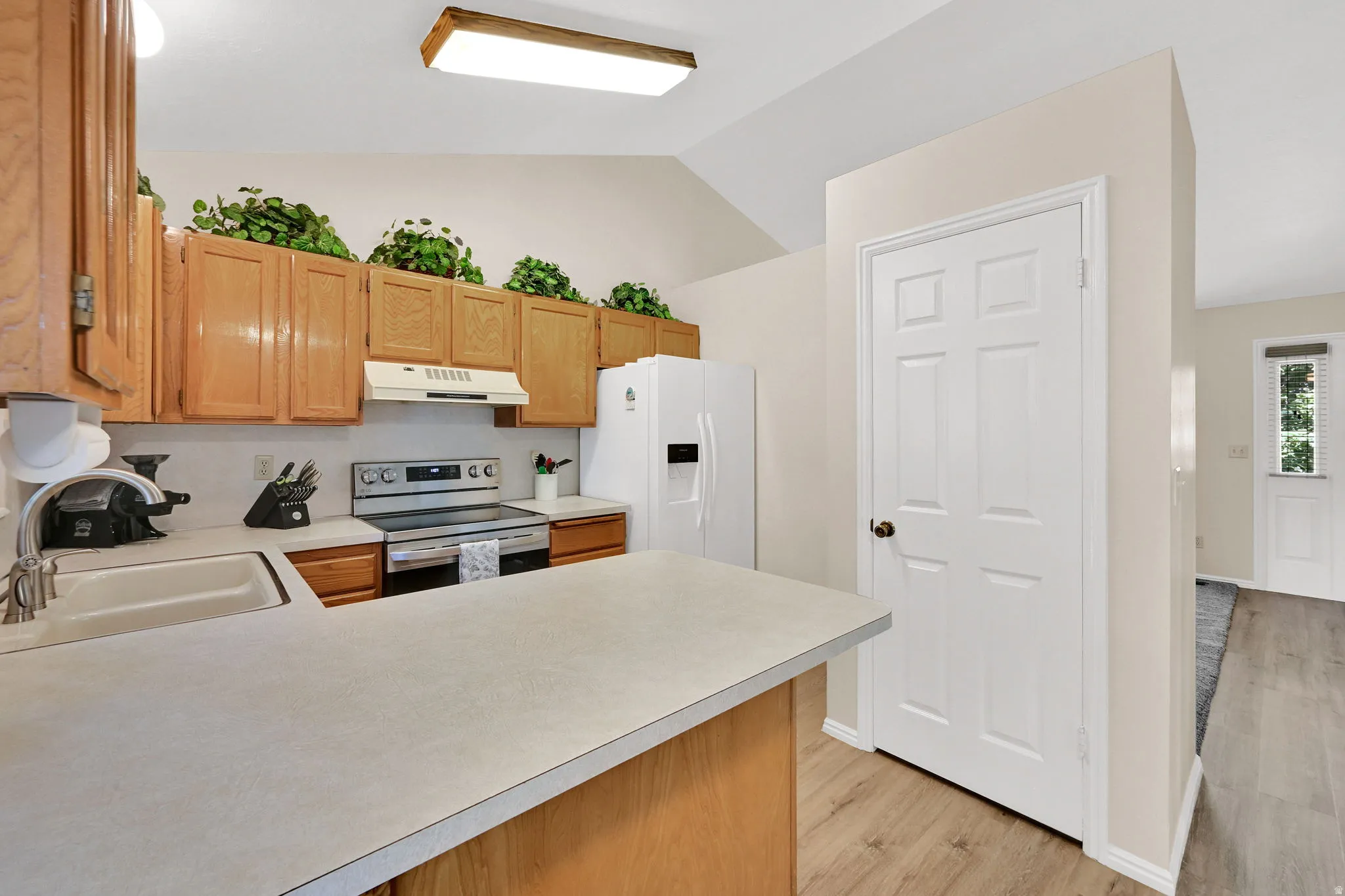 Kitchen featuring light wood cabinetry, a stainless steel range, and a white integrated sink