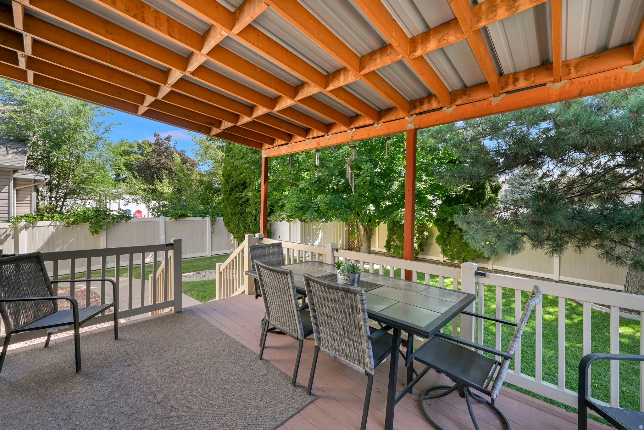 Covered wooden deck with a slatted wood ceiling, a metal roof, and white railings