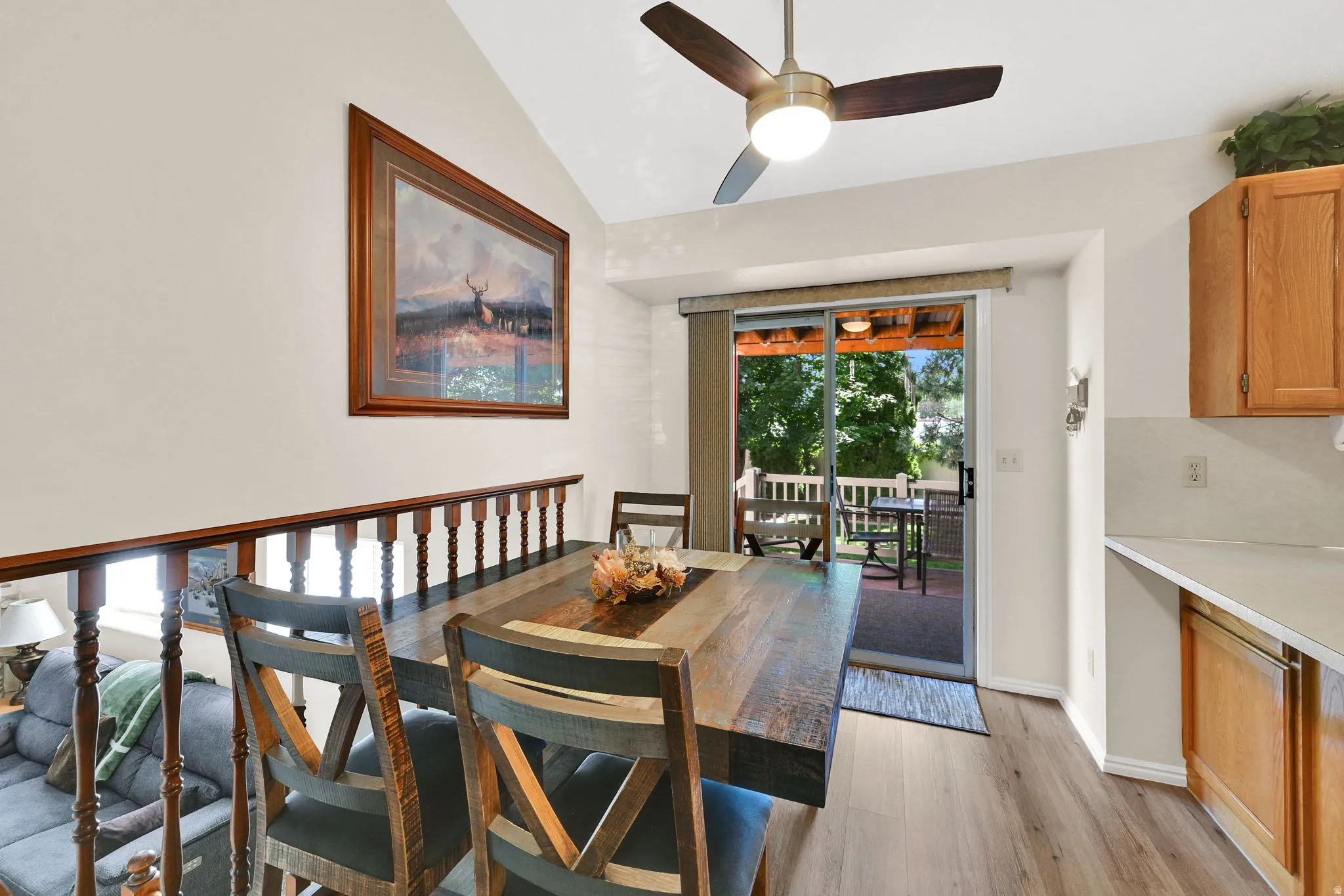 Dining area with wood-finish flooring, vaulted ceiling, and a ceiling fan