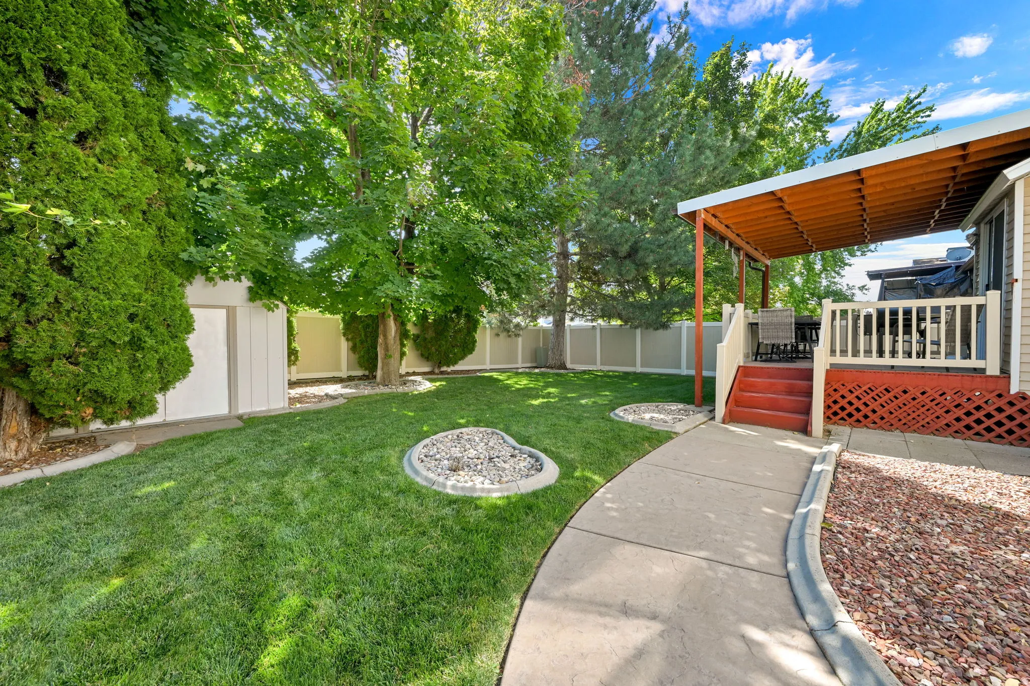 Expansive lawn with mature trees and a vinyl privacy fence