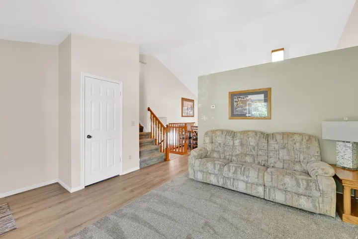 Comfortable family room showcasing neutral décor, wood-finish flooring, and sage green accent wall