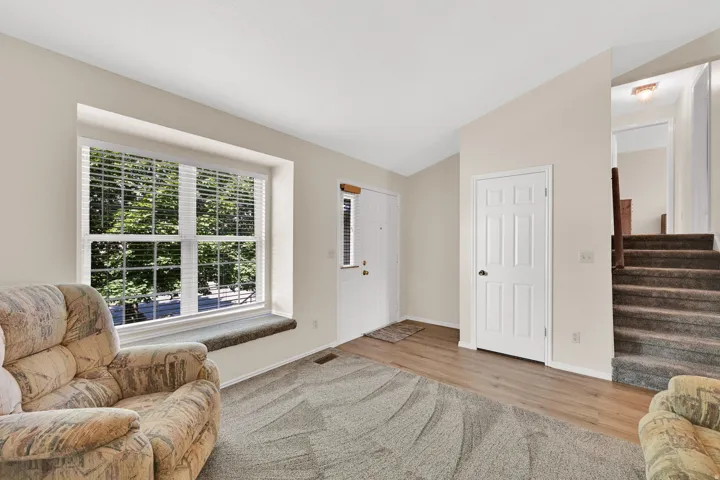 Entry area featuring a large window with blinds, wood-finish flooring, a six-panel interior door, and a carpeted staircase