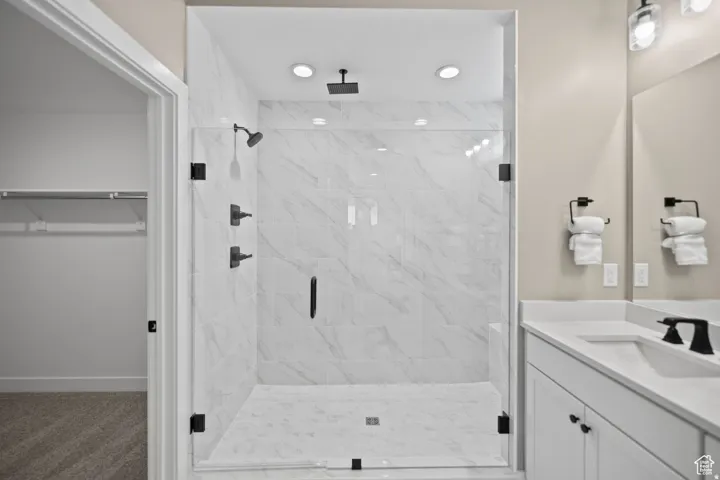 Spacious walk-in shower with clear glass enclosure and marble-patterned tile