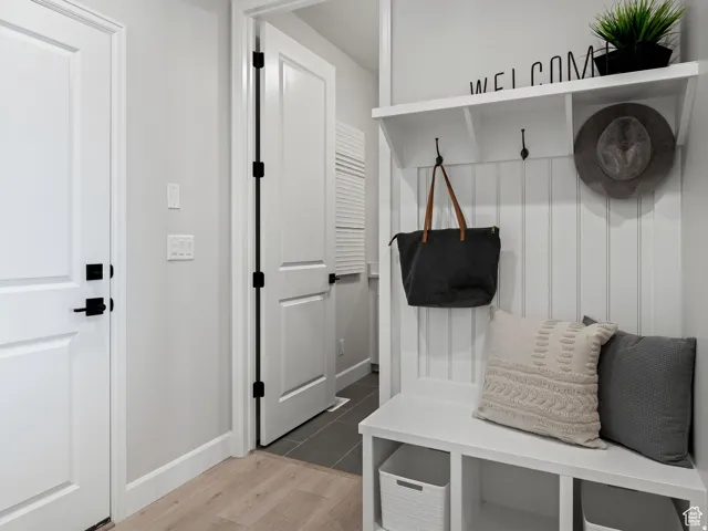 Entryway with wood-finish flooring, white trim, and a built-in hall tree featuring beadboard paneling, storage cubbies, and coat hooks