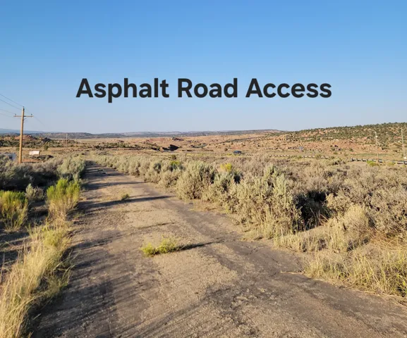 Asphalt road access surrounded by open land and natural vegetation
