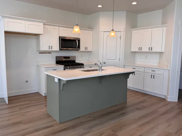 Contemporary kitchen featuring a contrasting island with a solid surface countertop and undermount sink
