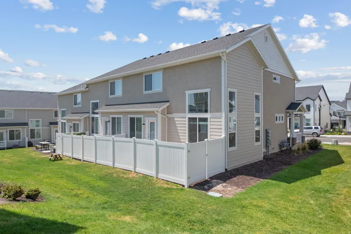 Rear exterior featuring a private white vinyl fence, stucco and siding finishes, multiple sliding glass doors, and a covered porch entry
