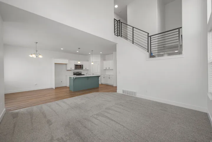 Open-concept living area featuring a kitchen with a teal island, white cabinetry, and stainless steel appliances