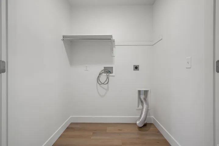 Dedicated laundry space featuring wood-finish flooring and a white color palette
