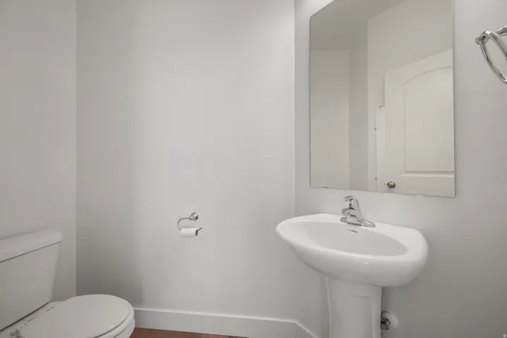 Pedestal sink with chrome faucet and rectangular wall-mounted mirror