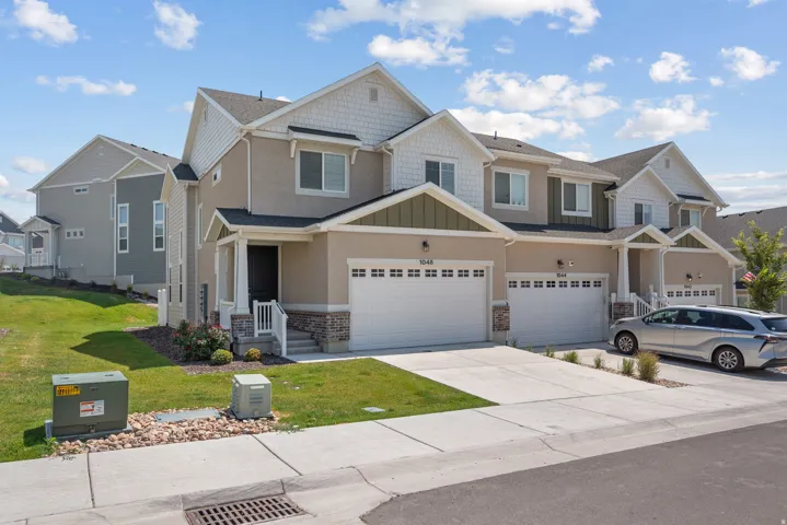 Contemporary townhome featuring a two-story elevation with mixed material siding, a single-car garage, and a covered porch entry