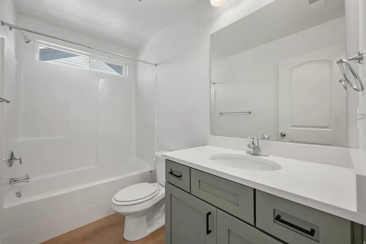 Spa-inspired primary bathroom featuring a dual-sink vanity with soft-close cabinetry in sage green, white quartz countertops, and brushed nickel hardware