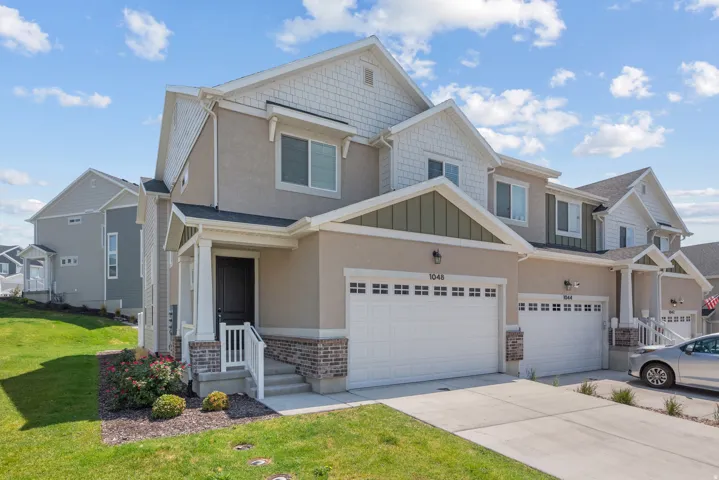 Multi-level residence featuring a covered entry, attached garage, and a combination of stucco and shingle siding