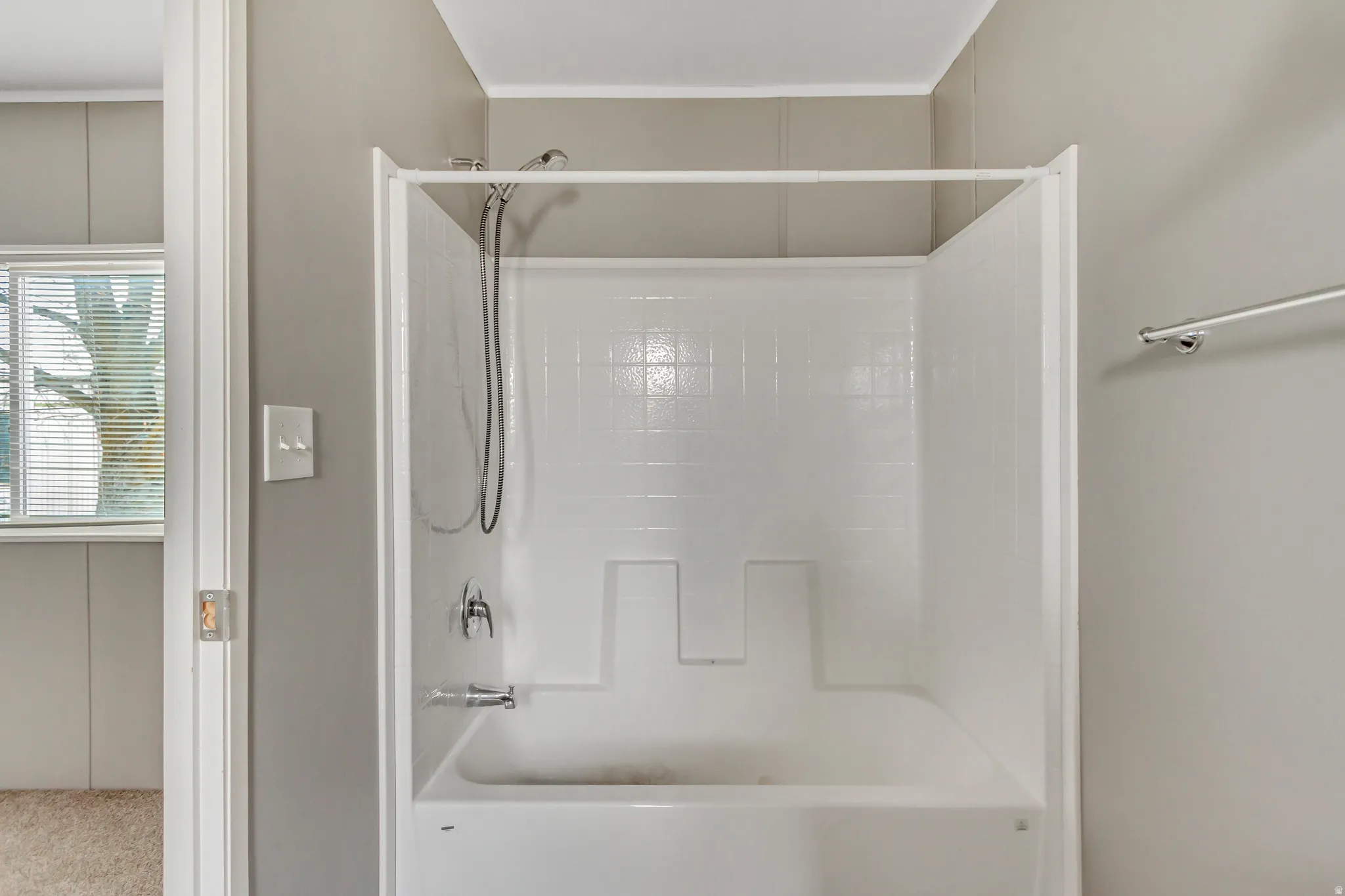 White fiberglass tub and shower combination with chrome fixtures