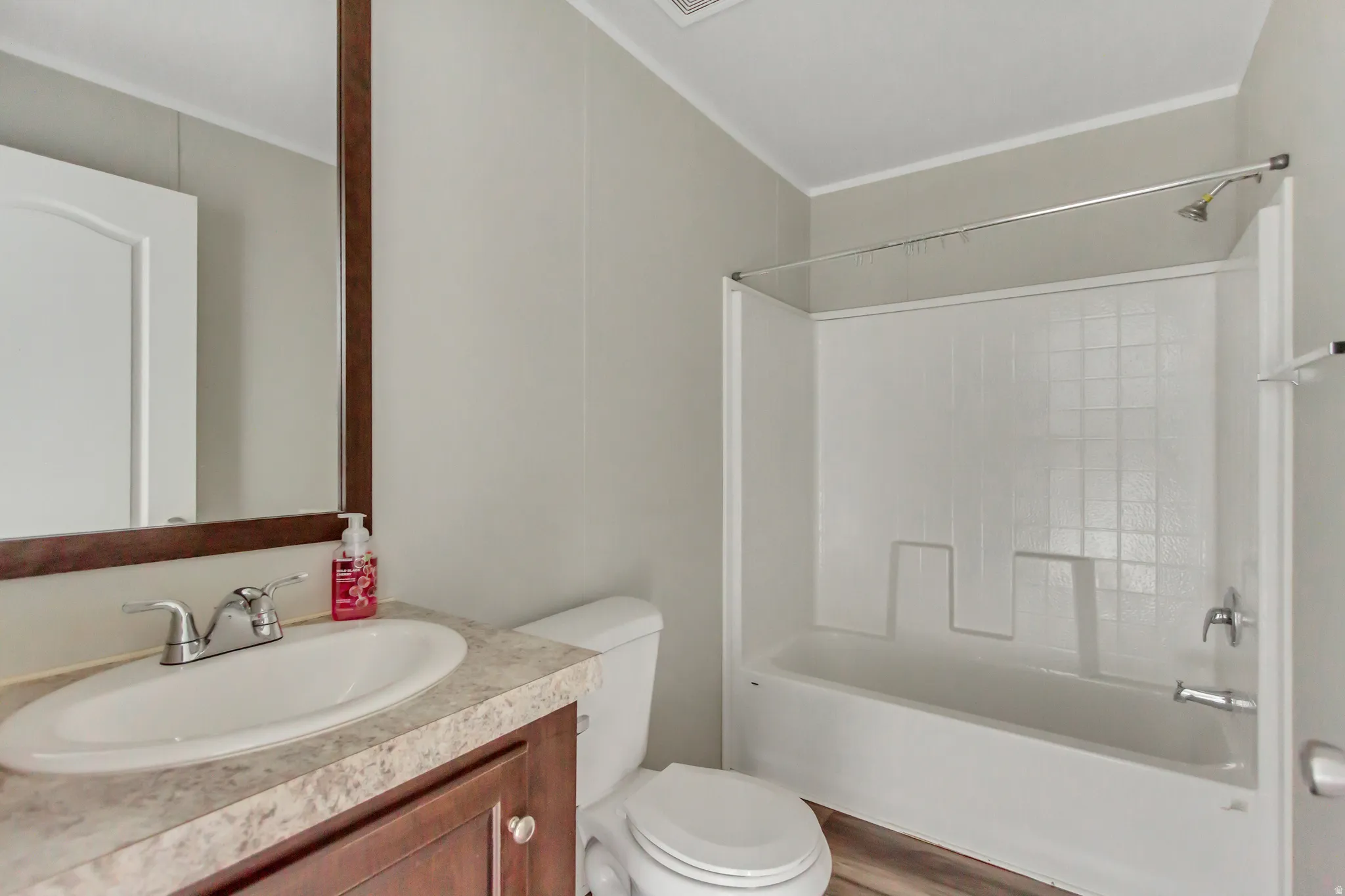 Spa-inspired bathroom featuring a wood-finish vanity with marble-look countertop, round undermount sink, and chrome fixtures