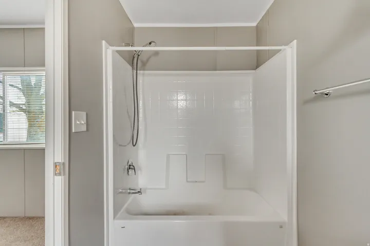 White fiberglass tub and shower combination with chrome fixtures
