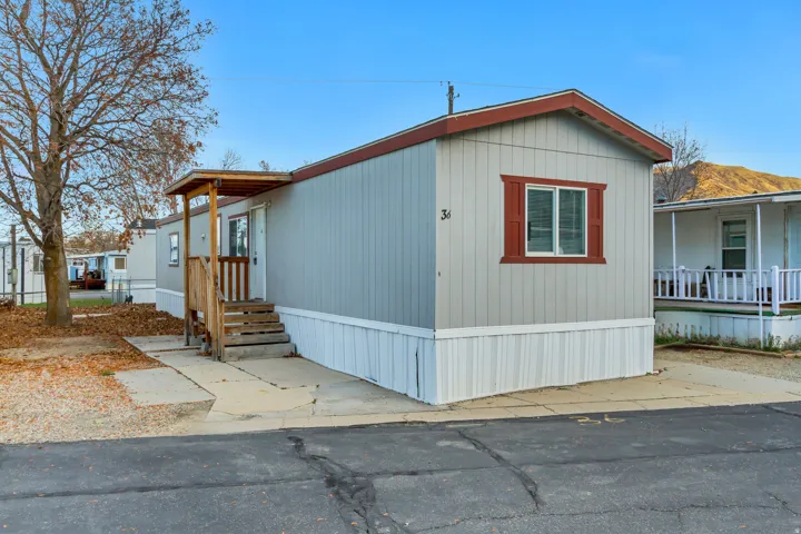 Light gray vertical siding exterior with white skirting and red trim accents