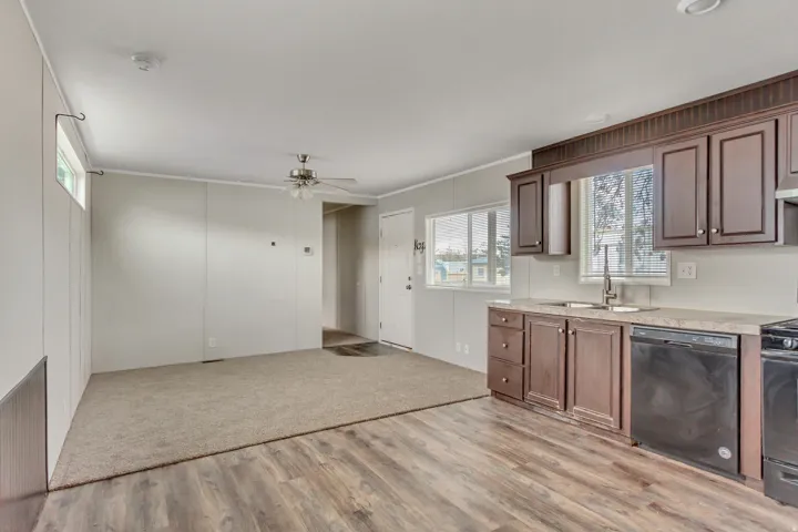 Kitchen featuring dark wood-finish cabinetry, light countertops, and a stainless steel sink with a gooseneck faucet