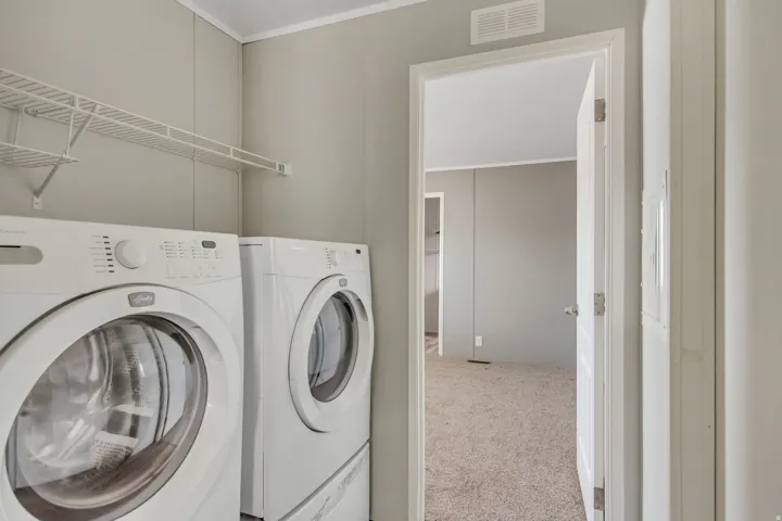 Laundry area with light gray paneled walls, white wire shelving, and overhead ventilation
