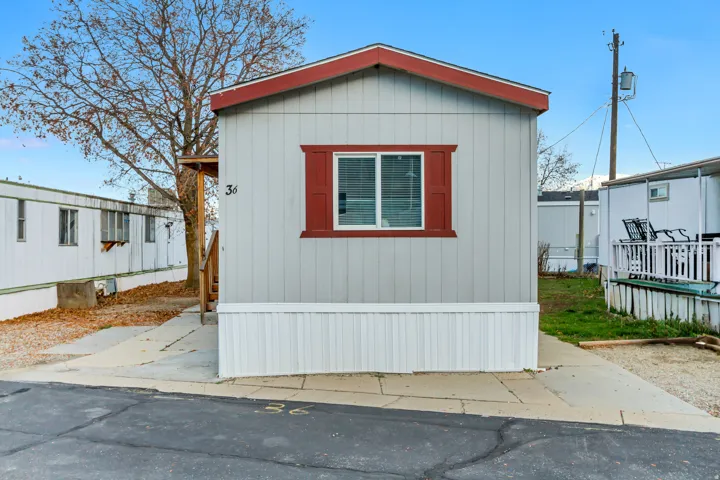 Charming manufactured home featuring a distinctive red-trimmed window and gable roof detail