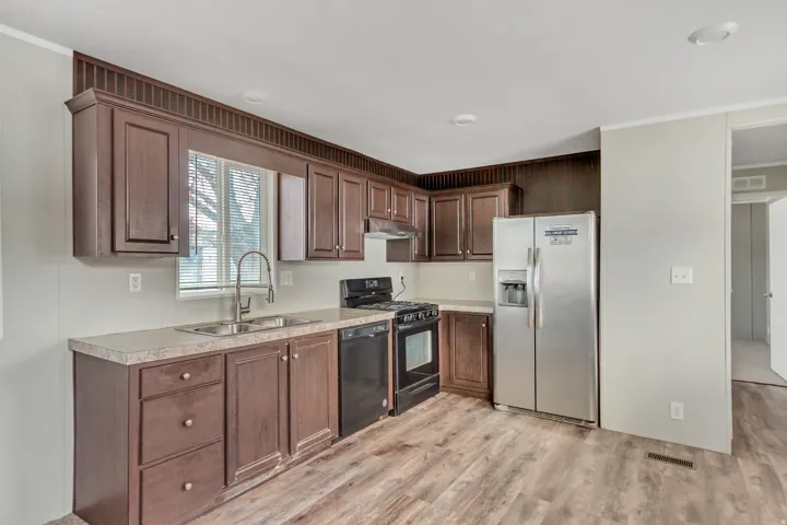 Kitchen featuring wood-finish cabinetry, granite-style countertops, and wood-finish flooring