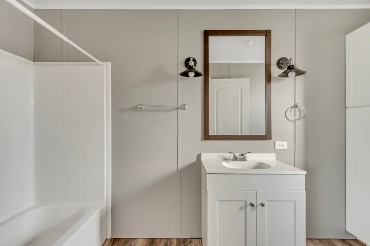 Bathroom featuring a white vanity with integrated sink, chrome faucet, and wood-finish flooring