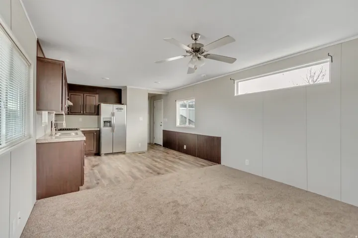 Open concept living area featuring wood-finish flooring, a ceiling fan, and horizontal accent window