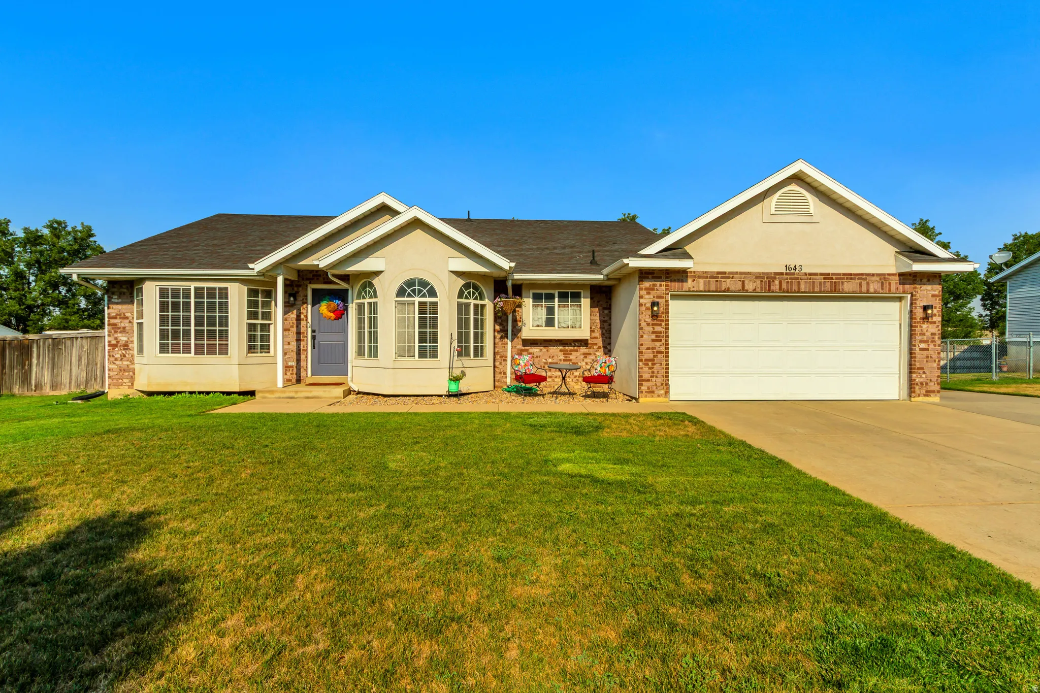 Charming single-story home featuring a cream and brick exterior with peaked rooflines and arched entryway details