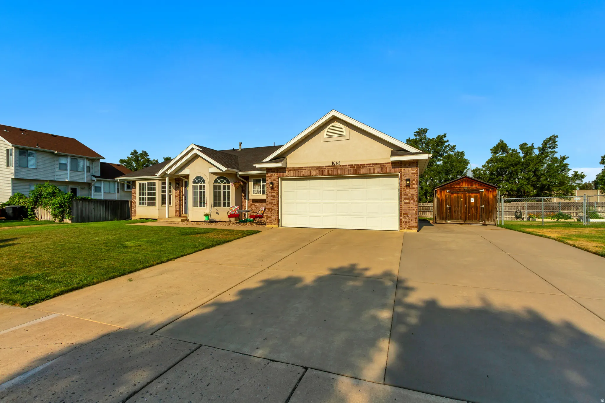 Charming one-story home featuring a cream-colored brick exterior with gable roofline and two-car attached garage