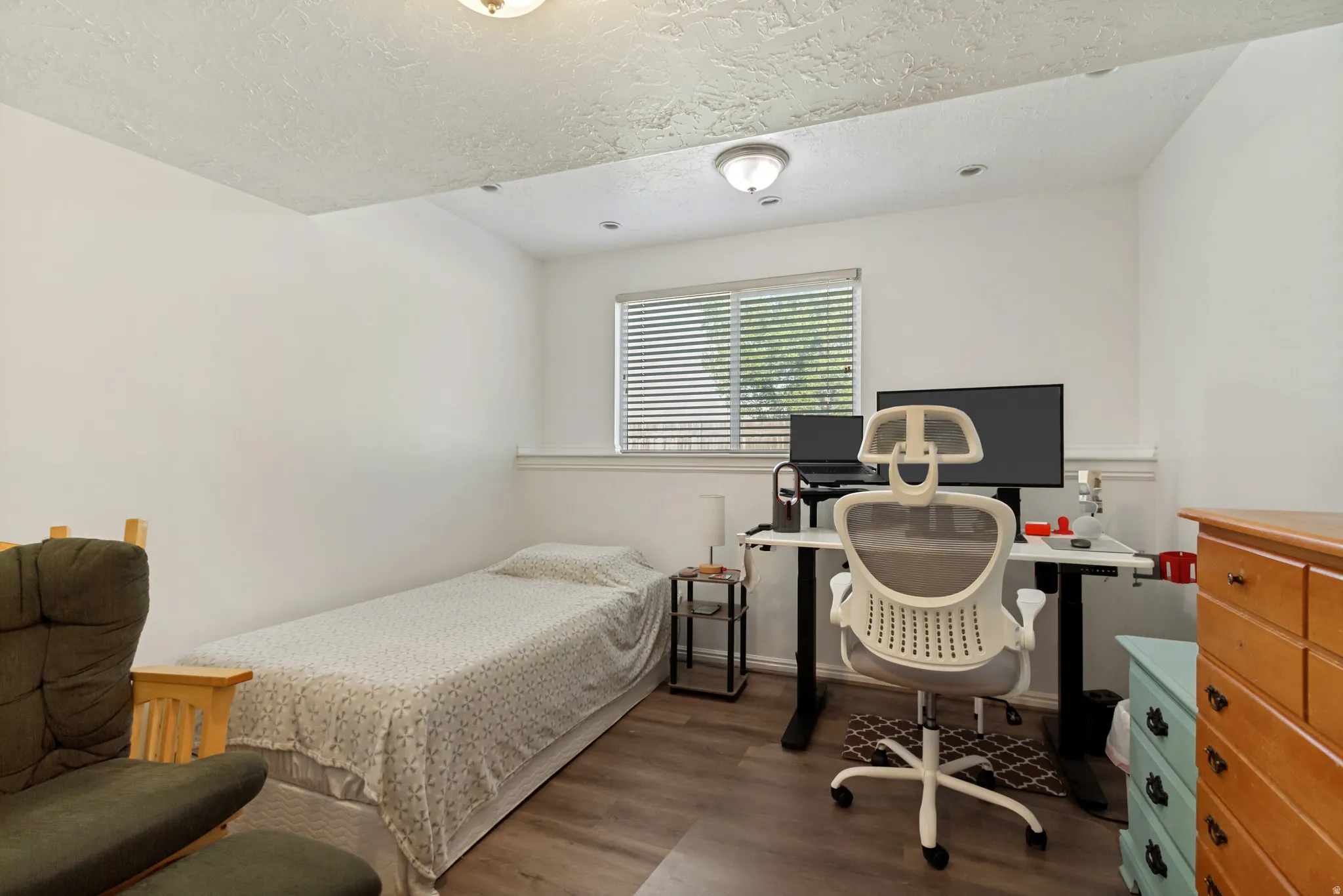 Compact room featuring wood-finish flooring, white walls, and a window with blinds