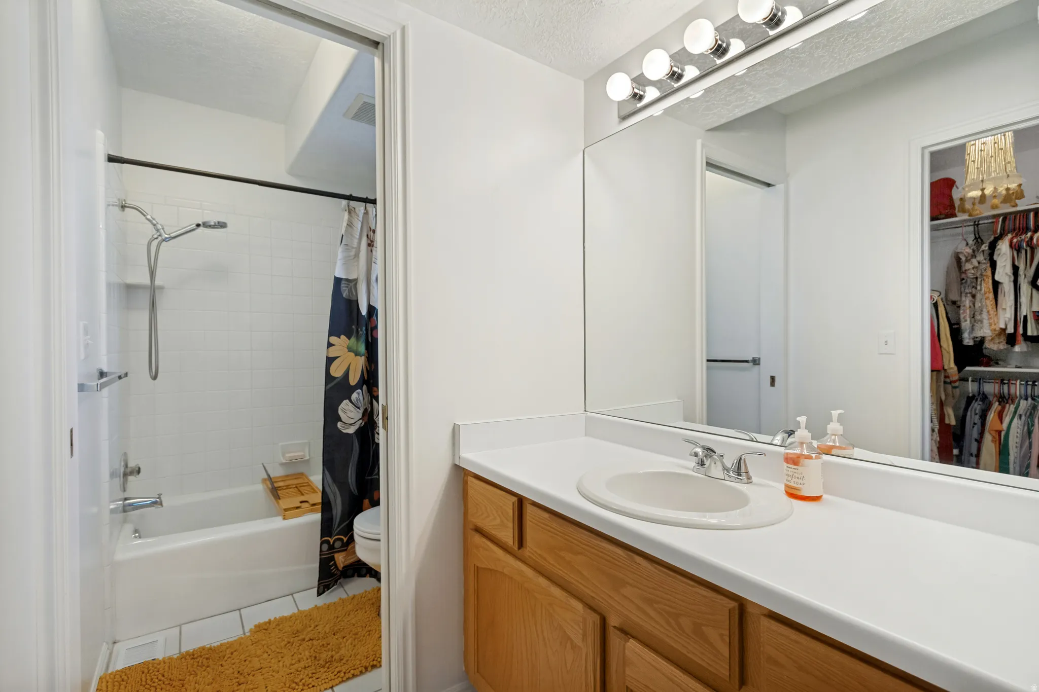 Bathroom vanity featuring a white countertop with an integrated sink, wood-finish cabinetry, and an expansive wall-mounted mirror