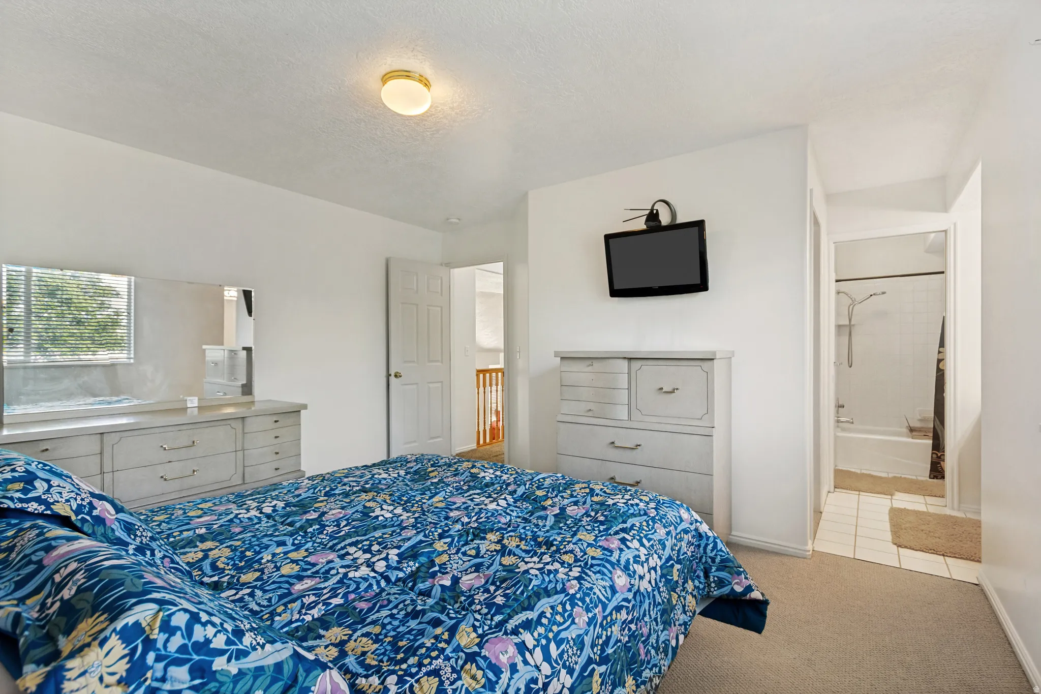 Bedroom featuring neutral carpeting, a window with horizontal blinds, and a standard ceiling light fixture