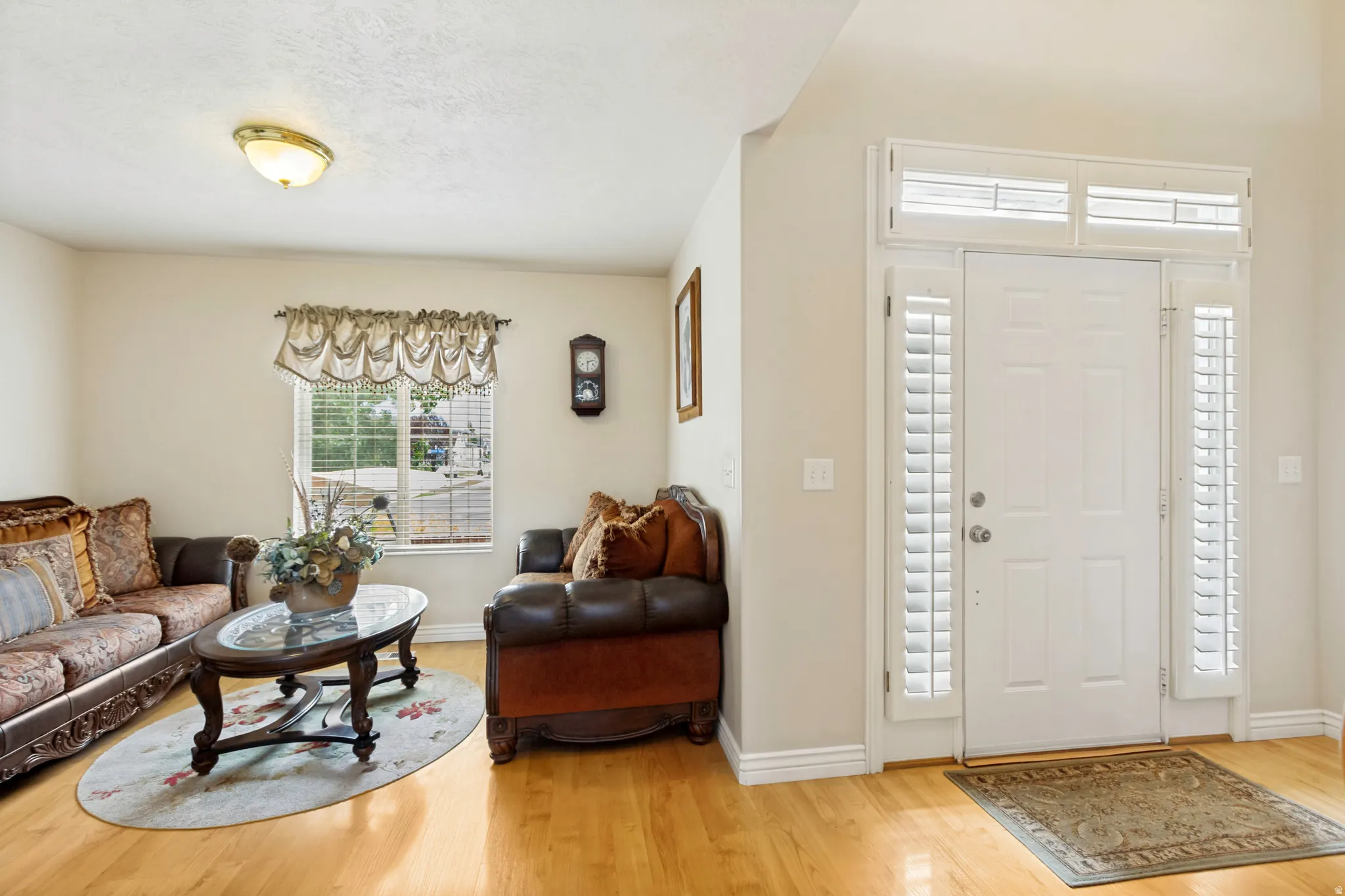 Entryway featuring a white door with sidelights, transom windows, and white plantation shutters