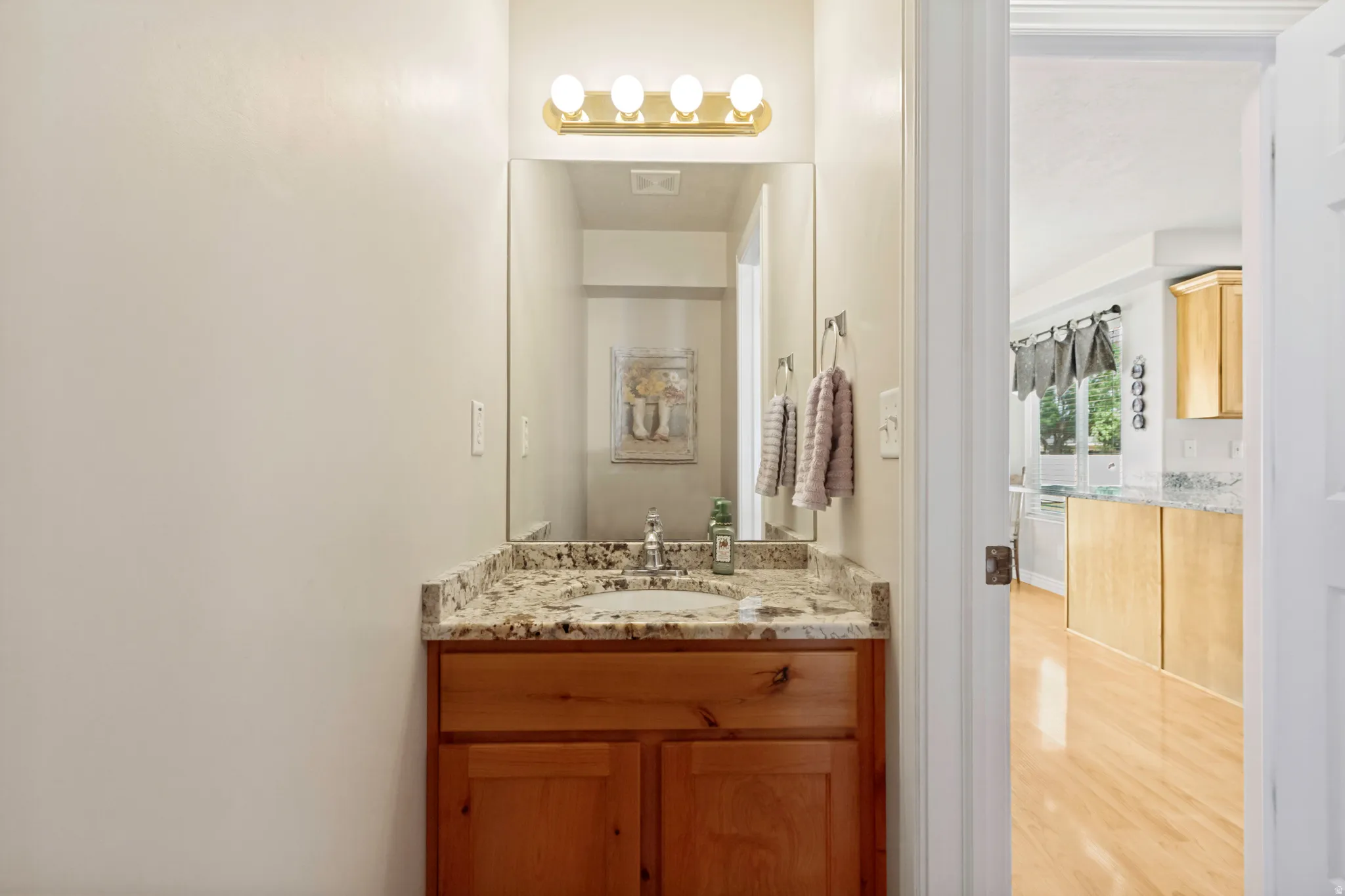Bathroom vanity featuring a granite-style countertop, undermount sink, and wood cabinetry